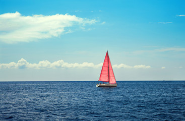 The boat with pink sail in calm blue sea