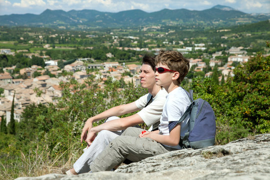 The young boy and adult man sit on top of hill