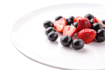 Fresh strawberries and black cherries on white plate
