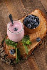 yogurt with blueberries in a glass jar and blueberries in a wood