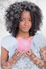 Composite image of young woman holding a pink piggy bank close
