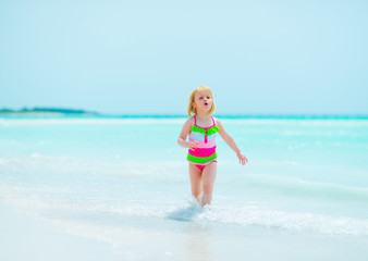 Fototapeta na wymiar Baby girl running on sea shore