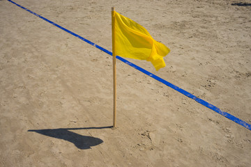 Yellow flag and the blue line in the sand beach