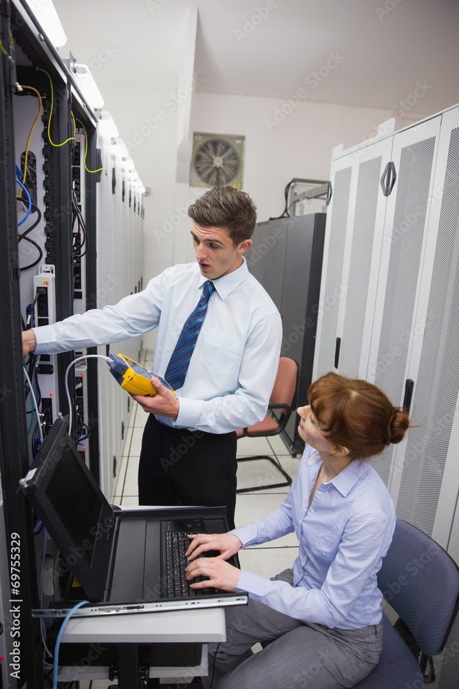Poster team of technicians using digital cable analyser on servers