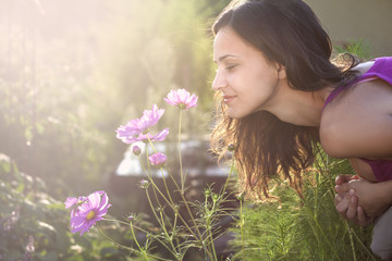 Naklejka premium Young beautiful woman smells a flower in the garden