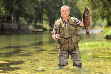 Papier Peint photo autocollant Pêcher Fier pêcheur tenant du poisson dans une rivière
