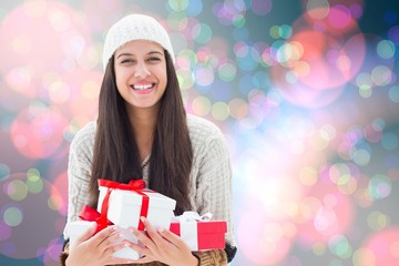 Composite image of festive brunette holding gifts