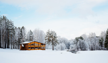 Wooden house in a nature area covered with freshly fallen snow.