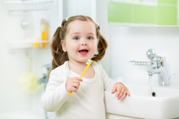 kid girl brushing teeth in bathroom