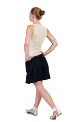 back view of walking  woman in dress. beautiful blonde girl in m