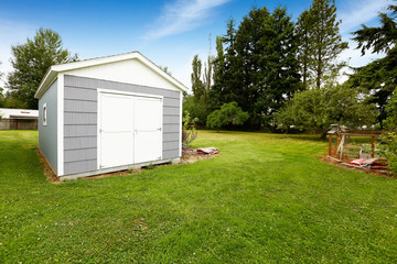 Fototapeta na wymiar Small grey shed with white trim. Countryside real estate