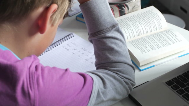 Boy Struggling With Written Homework In Bedroom