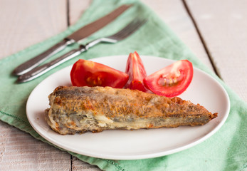 Shad grilled fish with tomato on a plate, green napkin