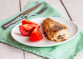 grilled fish with tomato on a plate, fork and knife