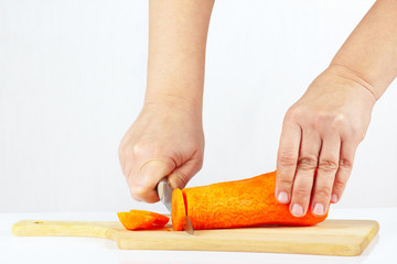 Women's hand with a knife cuts carrot