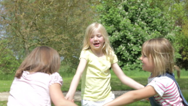 Three Girls Playing Ring-Around-The-Rosy Outdoors