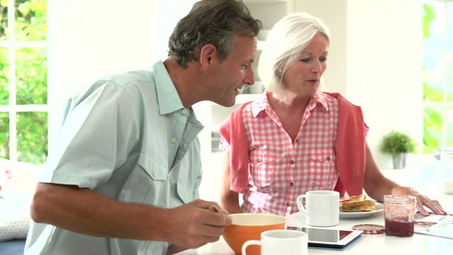 Middle Aged Couple Having Breakfast Together In Kitchen
