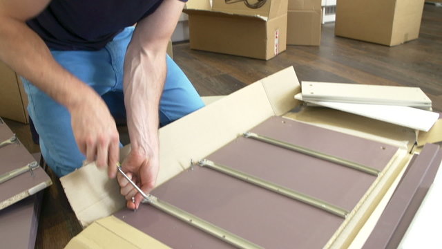 Man Putting Together Self Assembly Furniture In New Home