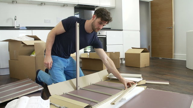 Man Putting Together Self Assembly Furniture In New Home