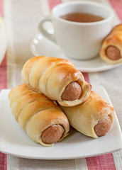 Hot-dog with sausages in a plate with tea and milk