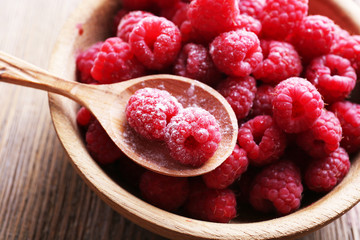 Ripe sweet raspberries in bowl on table close-up