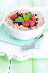 Tasty oatmeal with berries on table close-up