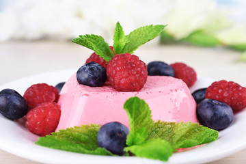 Heart shaped cake with berries on plate on wooden background