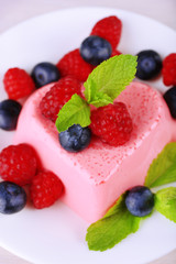 Heart shaped cake with berries on plate on wooden background