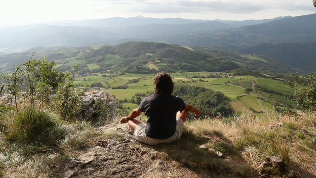 man sitting at the top of a mountain