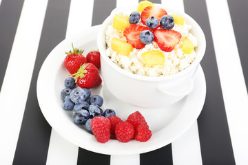 Cottage cheese with fruits and berries in bowl on table