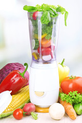 Blender with fresh vegetables on kitchen table