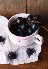 Purple grape in cup on wooden background