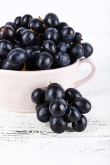 Purple grapes in bowl on wooden background