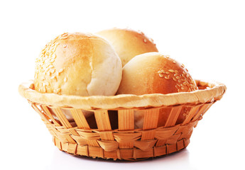 Tasty buns with sesame in wicker basket, isolated on white