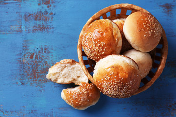 Tasty buns with sesame in wicker basket,