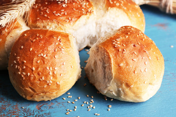 Tasty buns with sesame on color wooden background