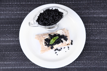 Slice of bread with butter and sauceboat with caviar