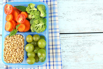 Tasty vegetarian food in plastic box on wooden table