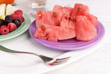 Slices of fruits with berries on plate on wooden table