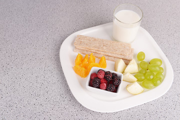 Slices of fruits with crispbreads and glass of milk