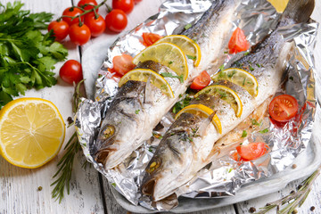 Tasty baked fish in foil on table close-up