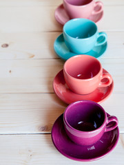 Colorful plates and saucers over wooden table background