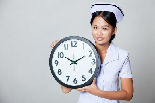 Young Asian nurse with a clock