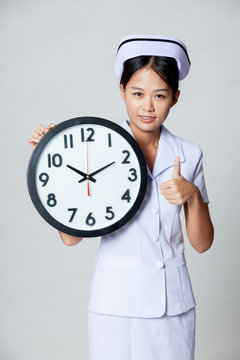 Asian young nurse show thumbs up with a clock