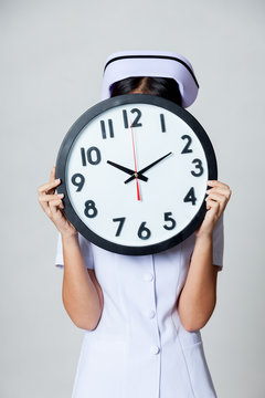 Asian young nurse close her face with a clock