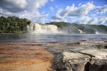 Beautiful powerful waterfall flowing into the lake