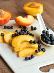 peach slices and blueberries in spoon on a white board