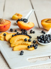 Slices of juicy peaches and blueberries on a white board
