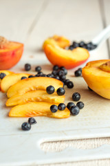 Slices of juicy peaches and blueberries on a white board