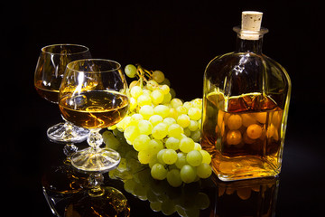 Bottle of brandy and two glasses and grapes